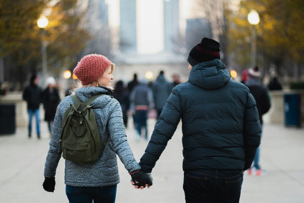 A couple holds hands on a winter day in an urban park, capturing warmth and connection.